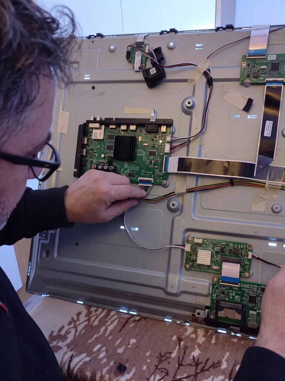 Televizyonun elektronik kart ve bağlantılarını inceleyen servis çalışanı